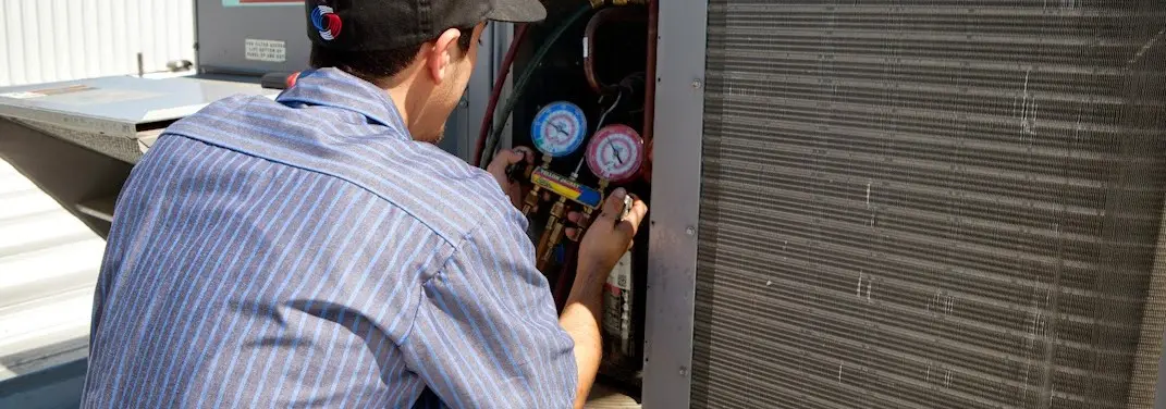 HVAC technician servicing a condenser unit in Englewood